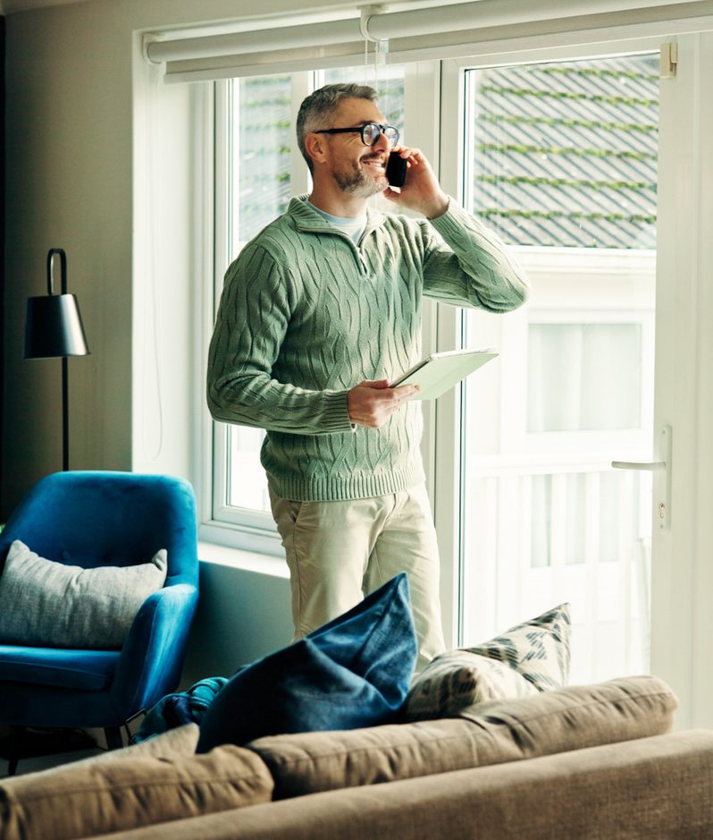 Man stands at window on phone smiling