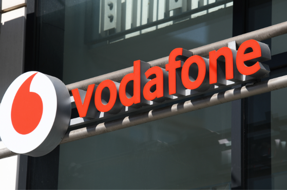 Vodafone storefront sign with bold red letters spelling vodafone and a white circular logo featuring a red teardrop, mounted on a metal frame above glass windows.