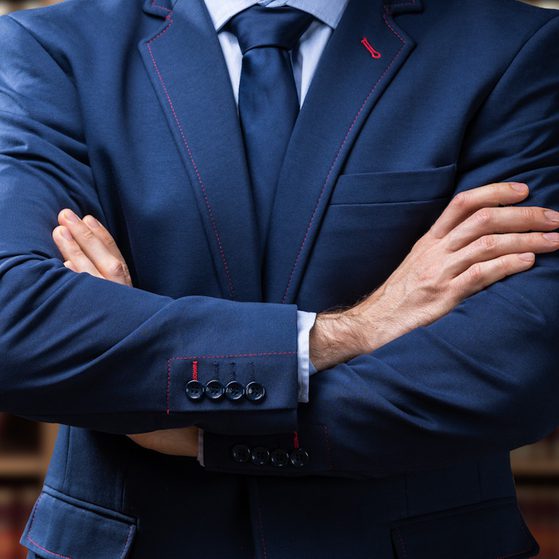 Lawyer standing arms crossed in front of bookshelf