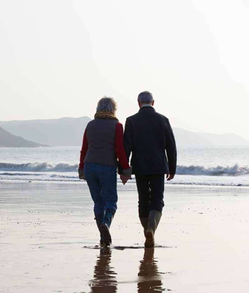 Mature couple walk along a beach