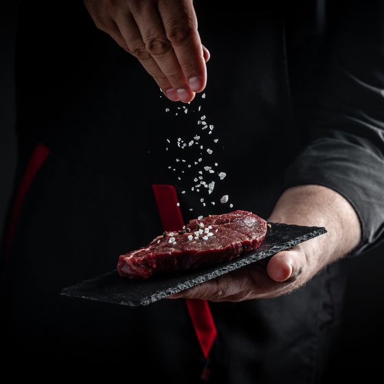 Chef sprinkling salt onto a steak