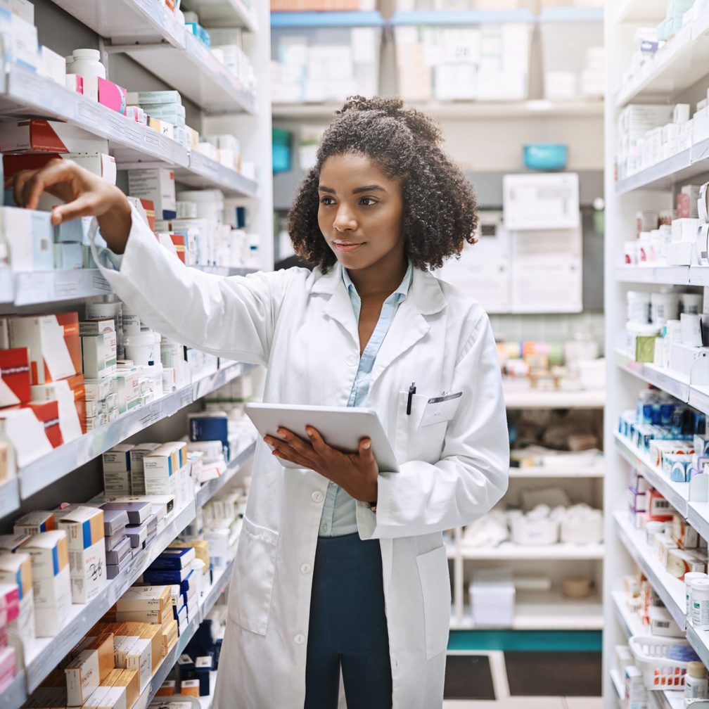 Pharmacist checking stock between shelves